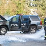 A South Kitsap Fire and Rescue firefighter cleans up after an engine fire that destroyed a Navy Region Northwest Police vehicle Dec. 14 in front of the Shell Food Mart at the intersection of Mile Hill Road and Woods Road. Firefighters sprayed water and foam to extinguish the fire. Bob Smith | Kitsap News Group