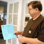 John Weatherill, club director of the Fred Needham VFW Post 2669 in Port Orchard, holds a permitting placard for his building posted by the county. Photo credit: Bob Smith | Kitsap Daily News