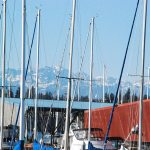 The striking signature of the Olympic Mountains are visible across Sinclair Inlet Sunday afternoon as snowy peaks appear behind yacht masts at the Port Orchard Marina. Photo credit: Bob Smith | Kitsap Daily News