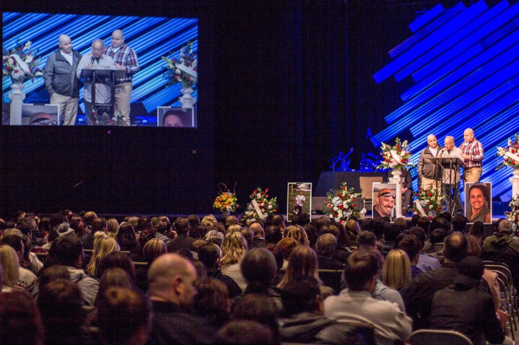 Family members assist Enrique Careaga, father of John D. Careaga, as he reads a tribute to his murdered son, daughter-in-law and grandsons, Feb. 7 at GracePoint Church in Bremerton. Sophie Bonomi / Kitsap News Group