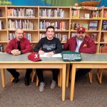 Anderson Crawford, middle, smiles as he signs with Shoreline Community College. Kingston head baseball coach Abe Lupkin, left, and coach Jack Nannery look on. Richard Henert / Contributed