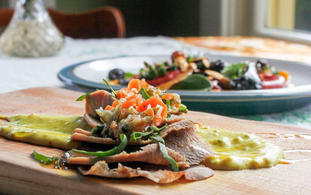 Pictured here is the cured beef tongue, served with a rosemary mustard sauce, mixed greens, sliced onion and chow chow relish. (Sophie Bonomi / Kitsap News Group)