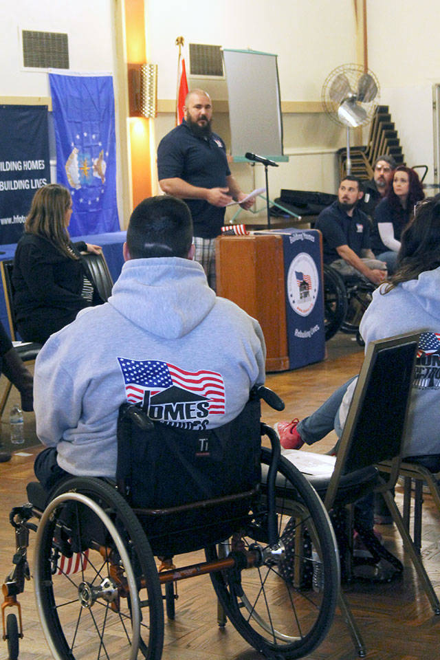 TSgt. Daniel Fye, at the podium, tells of the challenges of leading a normal life &mdash; and the blessing of soon having a home that will enable him to lead a normal life. In the foreground, one of a number of members of the Homes for Our Troops &ldquo;family&rdquo; of homeowners who traveled from as far away as Arizona to show their support. (Terryl Asla/ Kitsap News Group)