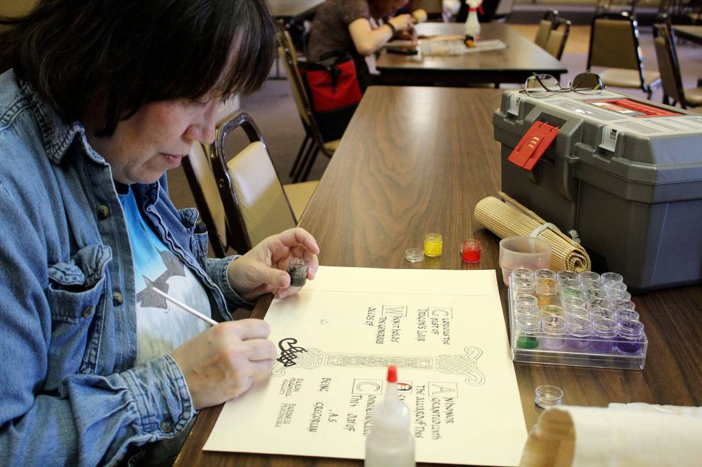 Rhiannon of Eagle&rsquo;s Flight paints the illumination on a charter page, a process that takes her a couple of hours. Custom pages, however, can take more than 40 hours of research, drawing and painting to complete.                                Michelle Beahm / Kitsap News Group