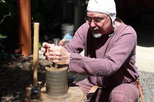 Arion the Wander demonstrates how, when striking a coin, one person usually holds the top and bottom dyes while a second strikes the coin to imprint the design on both sides.                                Michelle Beahm / Kitsap News Group