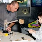 A child and caregiver create a hydraulic lift at Summer STEAM at the Naval Undersea Museum in 2016.                                Photo courtesy of the U.S. Naval Undersea Museum