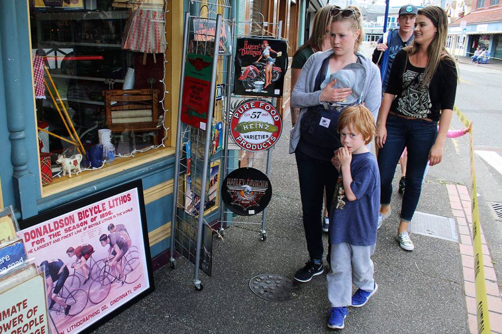 A shopper checks out a reproduction of an antique cycling sign outside a downtown Poulsbo antique shop June 3 during the Poulsbo Twilight Criterium. (Richard Walker/Kitsap News Group)