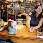 Kate at Liberty Bay Books watches the Poulsbo Twilight Criterium from inside the store, June 3. (Richard Walker/Kitsap News Group)