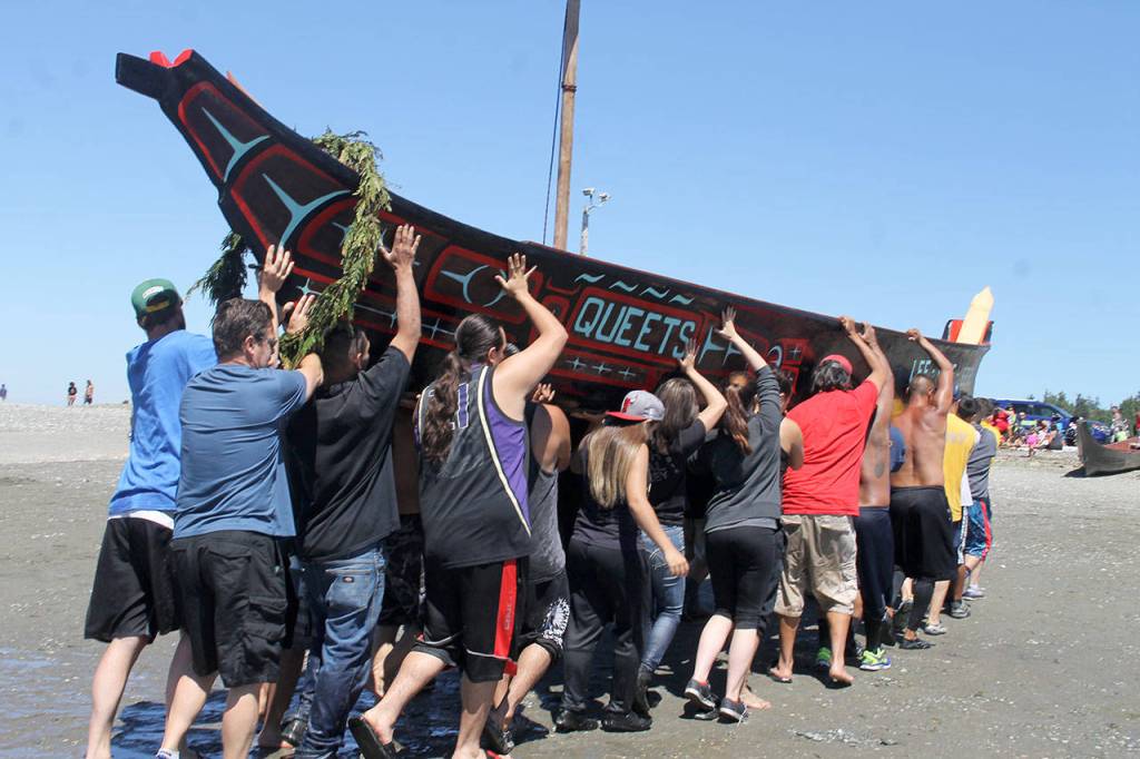 Volunteers carry a canoe from Queets, on the Pacific Coast, out of the tideline at Point Julia during the 2016 Canoe Journey. (Richard Walker)