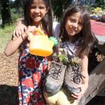 Tamiko Metzger-Ortega, age six, waters the plants she and eight-years old Dakota Ortega planted in a pair of size 14 athletic shoes.                                Terryl Asla/Kitsap News Group