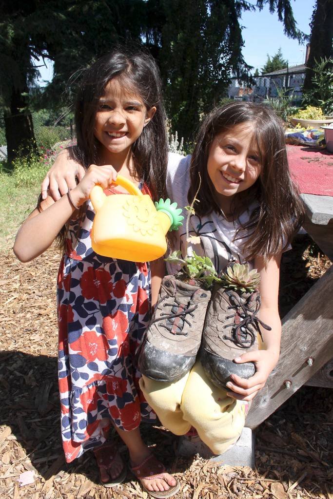 Tamiko Metzger-Ortega, age six, waters the plants she and eight-years old Dakota Ortega planted in a pair of size 14 athletic shoes.                                Terryl Asla/Kitsap News Group