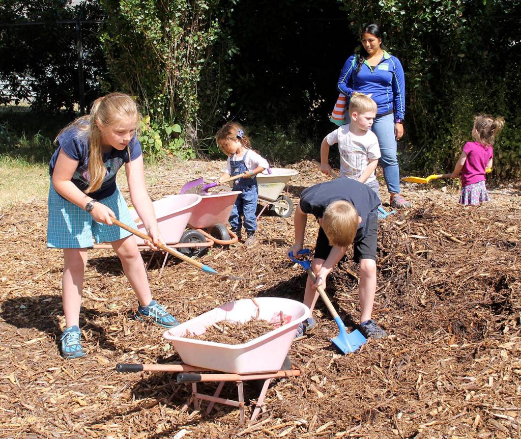 Youngsters load mulch to spread on the Raab Park Youth Garden. The program, which meets wekkly on Monday, is open to children ages two to 12 years. Often, when the young people get into high school, they will return to serve as volunteers and mentors, officials said.                                Terryl Asla/Kitsap News Group