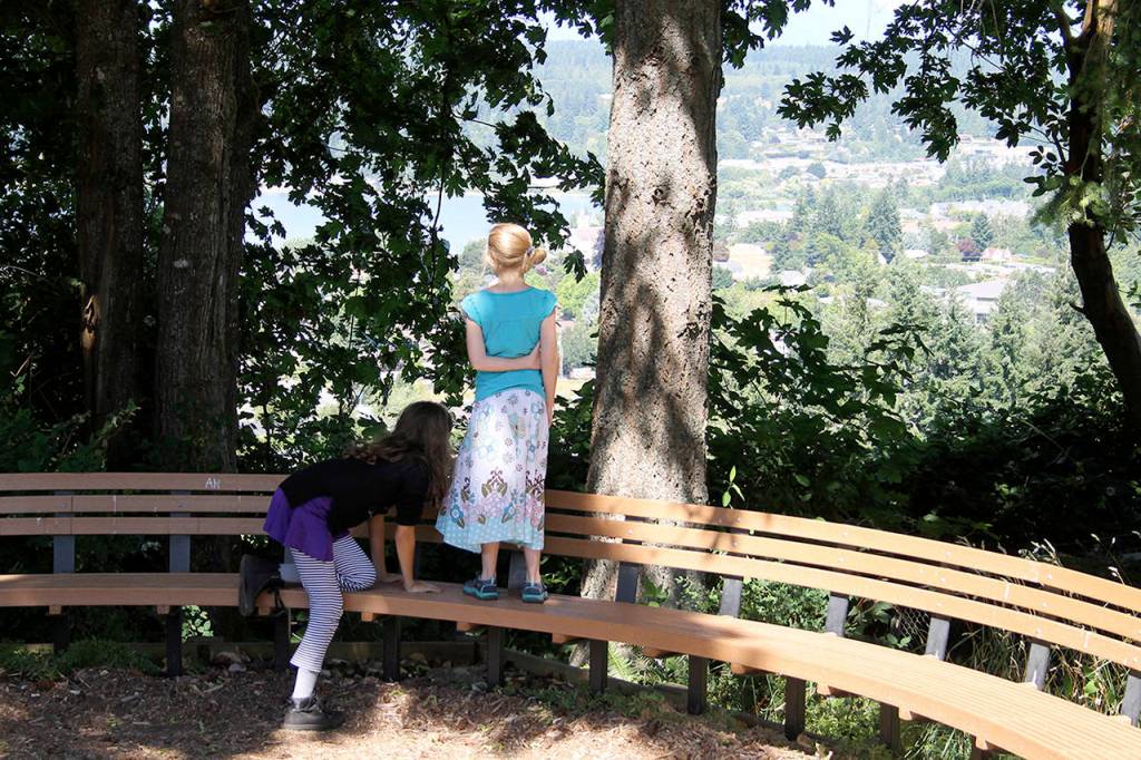 Abi Ferguson, age 11, climbs up onto the bench to be with Jacqui Conger, age 8, as they admire the panoramic view of Liberty Bay from the overlook at Raab Park.                                Terryl Asla/Kitsap News Group