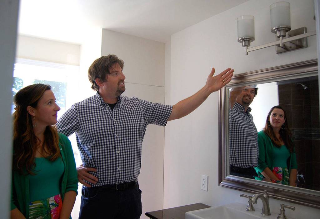 Scott Studerus, with wife Kim looking on, shows their handiwork remodeling the small home&rsquo;s bathroom. Photo: Bob Smith | Kitsap Daily News