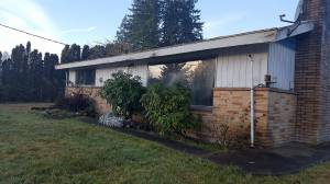 The two-bedroom, one-bath rambler on Mitchell Road in Port Orchard (shown here before the flip began) was in miserable shape &mdash; a tarp covered a leaky roof, the windows were defective and not energy efficient, and there were holes in the ceiling. Photo: Courtesy of Scott Studerus.