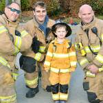 Young resident Owen gets to stand with firefighters Tony Parker, Justin Foley and Josh Foley at the Bainbridge Fire Department pancake breakfast on Oct. 14. (Mark Krulish/Kitsap News Group)