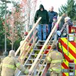 Firefighters help residents get on and off the top of the truck. (Mark Krulish/Kitsap News Group)
