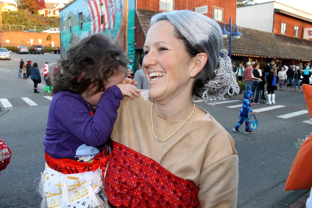 Left, Jodi Blackmore of Poulsbo laughs as her daughter Amelia, dressed as the lead character from the film &ldquo;Moana,&rdquo; gets camera shy, Oct. 31 in downtown Poulsbo. Right, Poulsbo Police Chief Dan Schoonmaker sports a police department patch in pink for Breast Cancer Awareness Month, and whiskers for &ldquo;Movember,&rdquo; a global effort to call attention to men&rsquo;s health issues. Richard Walker/Kitsap News Group
