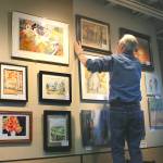 Garven Kinley places PAL paintings on Central Markets upstairs wall.