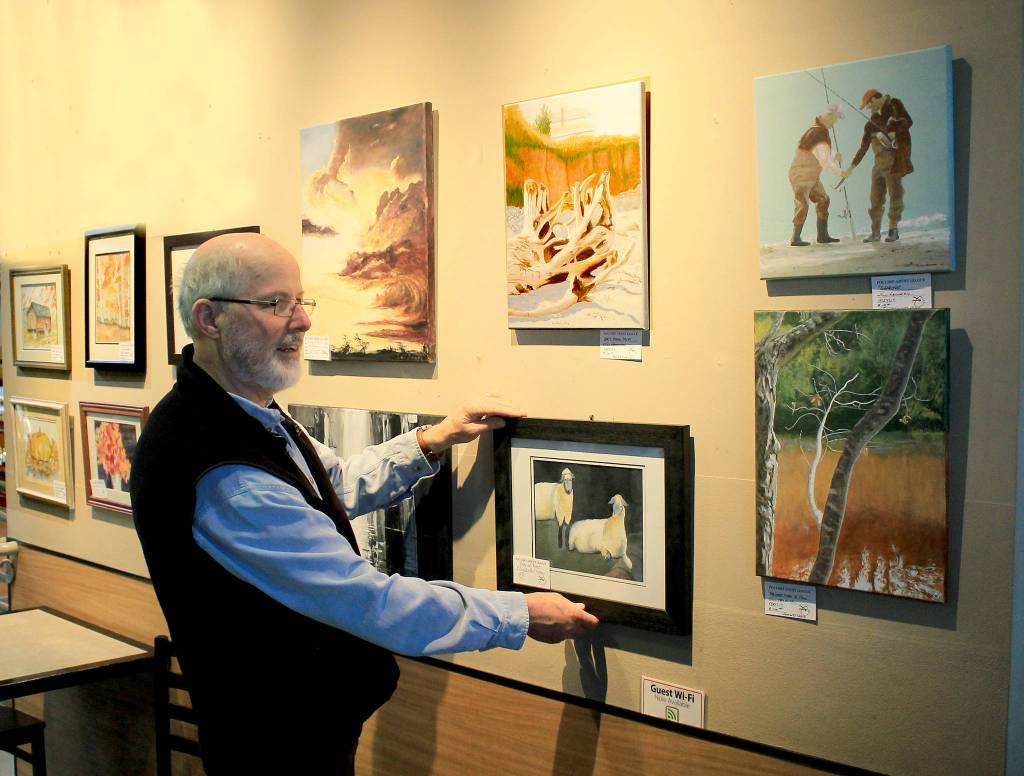 Bill Fulton, current PAL President, lines up fellow artists paintings at Central Market.