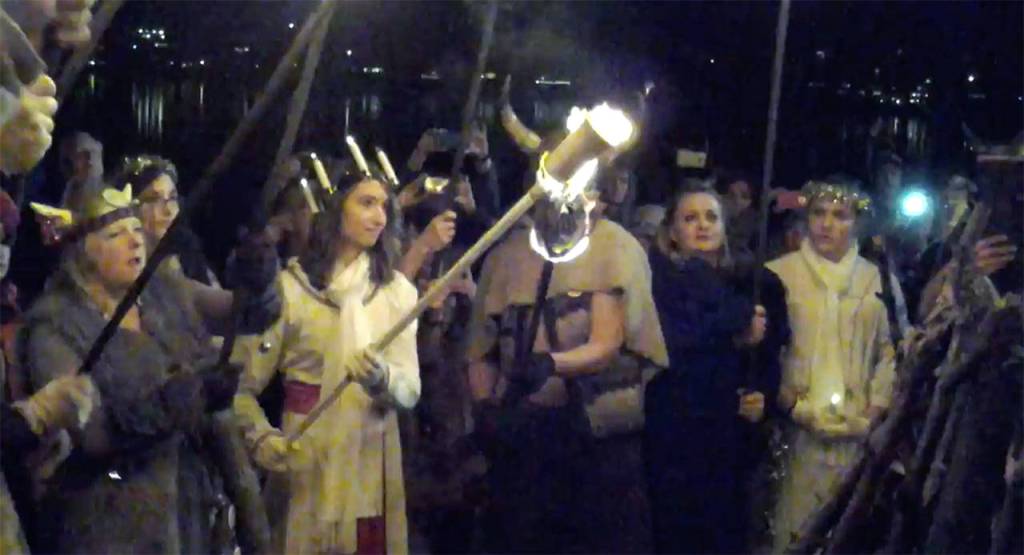 The Lucia Bride, Kaitlyn Bell, prepares to lower her torch onto the Julefest bonfire, Dec. 2 at Muriel Iverson Williams Waterfront Park. (Richard Walker/Kitsap News Group)