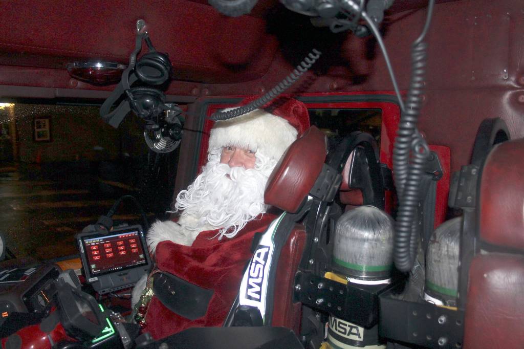Santa Claus rides shotgun in the firetruck as it approaches Kingstons Mike Wallace Park. Nick Twietmeyer | Kitsap News Group.