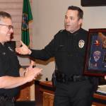 Deputy Police Chief Andy Pate receives a shadow box from Poulsbo Police Chief Dan Schoonmaker in recognition of Pates career with the department. Nick Twietmeyer/Kitsap News Group.