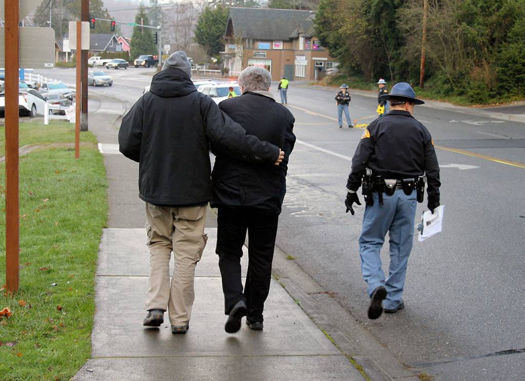 The driver of a vehicle that struck a woman in a crosswalk is embraced by her husband as they walk down Front Street, Dec. 15. (Richard Walker/Kitsap News Group)
