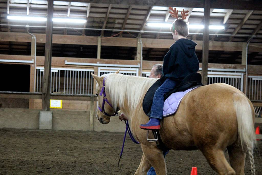 Trainers from The Riding Place led horses ridden by the foster children, some of whom had never seen a horse in person before the Dec. 22 event.                                Michelle Beahm / Kitsap News Group
