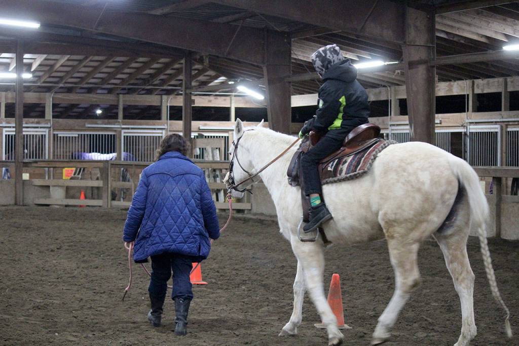 Trainers from The Riding Place led horses ridden by the foster children, some of whom had never seen a horse in person before the Dec. 22 event.                                Michelle Beahm / Kitsap News Group
