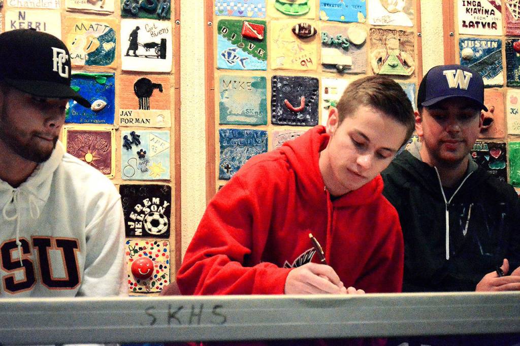 Boys soccer player Grant Larson, sitting between baseball players Dusty Garcia and Drew Worden, signs on to play at Northwest Nazarene University in Idaho.