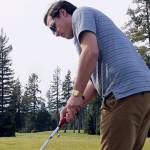 Senior Connor Lowe putting during a March 12 practice at Gold Mountain Golf Course while teammate Joel Angkico watches.