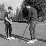 Senior Bryce Kahle, left, helps freshman Mathew Quall during practice at Gold Mountain Golf Course on March 12. (Jacob Moore/Kitsap News Group)