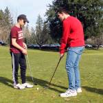 Senior Bryce Kahle, left, helps freshman Mathew Quall during practice at Gold Mountain Golf Course on March 12. (Jacob Moore/Kitsap News Group)