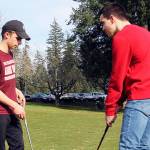 Senior Bryce Kahle, left, helps freshman Mathew Quall during practice at Gold Mountain Golf Course on March 12. (Jacob Moore/Kitsap News Group)