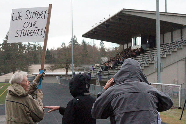 Supporters hold a sign and cheer on the students during a walkout. Photo by Nick Twietmeyer