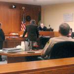 Clinton R. Caldwell, 67, of Sequim appears on a television monitor in Clallam County Superior Court on Tuesday as Chief Criminal Deputy Prosecuting Attorney Michele Devlin and attorney John Hayden stand before Superior Court Judge Chris Melly in Port Angeles. Witnessing the proceeding from the prosecutors table were Clallam County Sheriff William Benedict and Port Angeles police Chief Brian Smith. (Keith Thorpe/Peninsula Daily News)