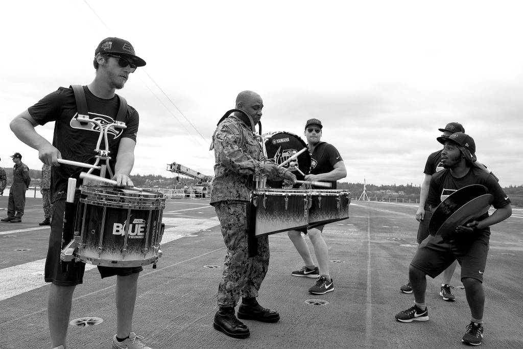 <em>Cmdr. Rodney Moss, from Concord, North Carolina, and the Seattle Seahawks drumline, Blue Thunder, perform aboard the aircraft carrier USS John C. Stennis (CVN 74).</em>                                Mass Communications Specialist Seaman Angelina Grimsley / U.S. Navy