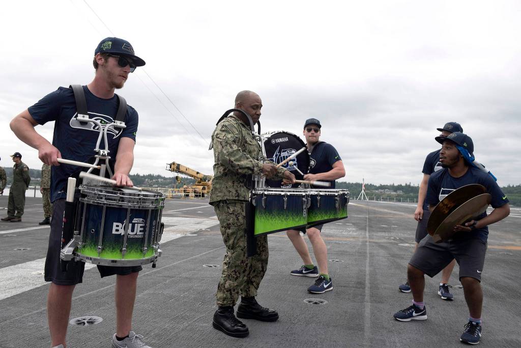 <em>Cmdr. Rodney Moss, from Concord, North Carolina, and the Seattle Seahawks drumline, Blue Thunder, perform aboard the aircraft carrier USS John C. Stennis (CVN 74).</em>                                Mass Communications Specialist Seaman Angelina Grimsley / U.S. Navy