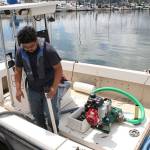 Joseph Fernandez with Terry & Sons, a mobile marine pump-out service, demonstrates the proper method of pumping waste water out of a boat. Nick Twietmeyer / Kitsap News Group.