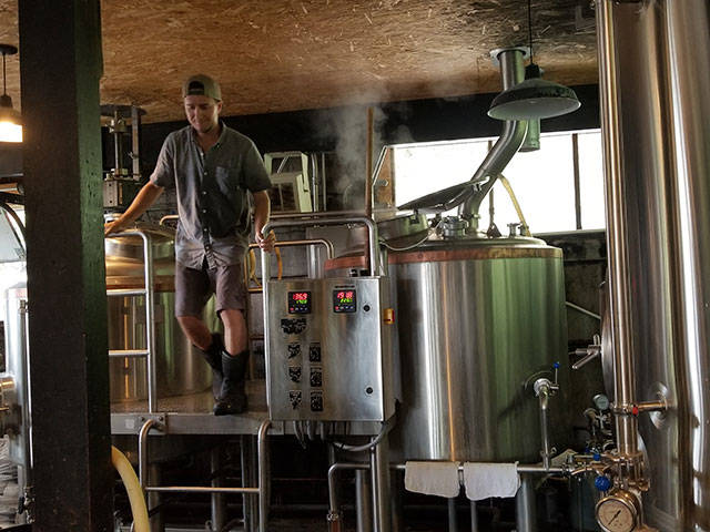 <em>Brewmaster Jared Snyder jumps down from the kettle while brewing at Poulsbos Valhöll Brewing. </em>