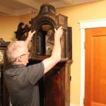 George Pease removes part of the case of one of his many clocks to show the inner workings of the clocks movement and the nest of bells which give the clock its chime. Nick Twietmeyer | Kitsap News Group.