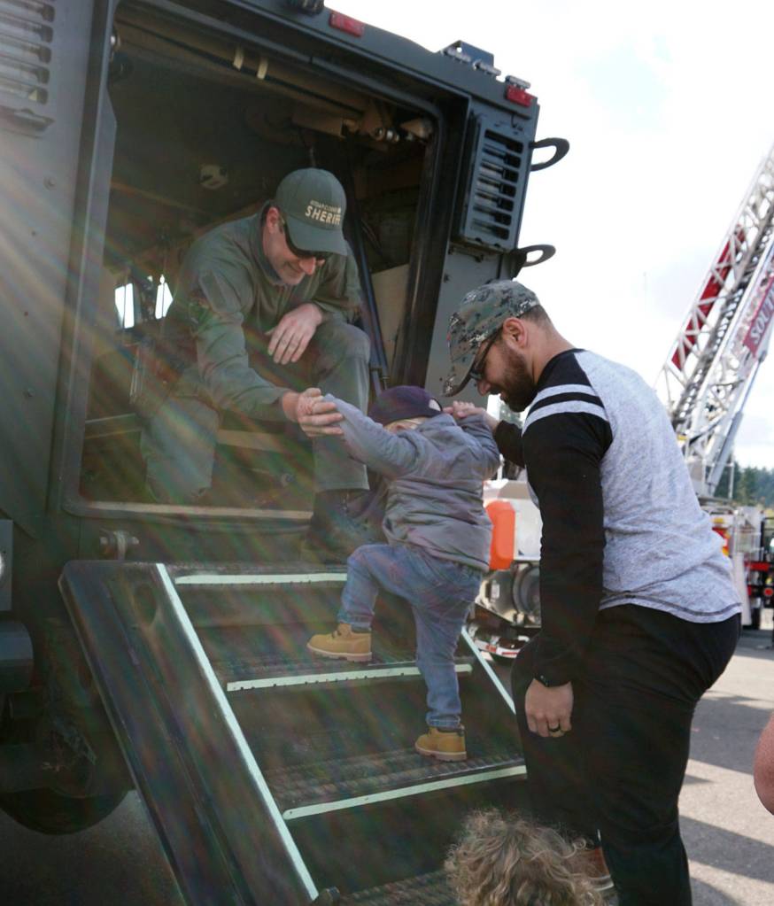 With the help of his father Jason, Jedi Minters and his cousin climb aboard a Kitsap County Sheriffs Office armored rescue vehicle. (Bob Smith | Kitsap Daily News)
