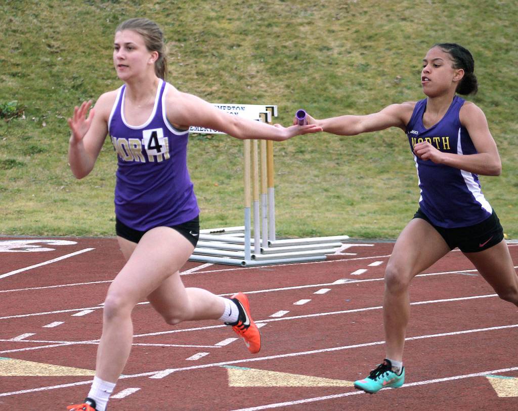 Emma Orness takes the baton from Kamora McMillian in the 4x100 relay. (Mark Krulish/Kitsap News Group)