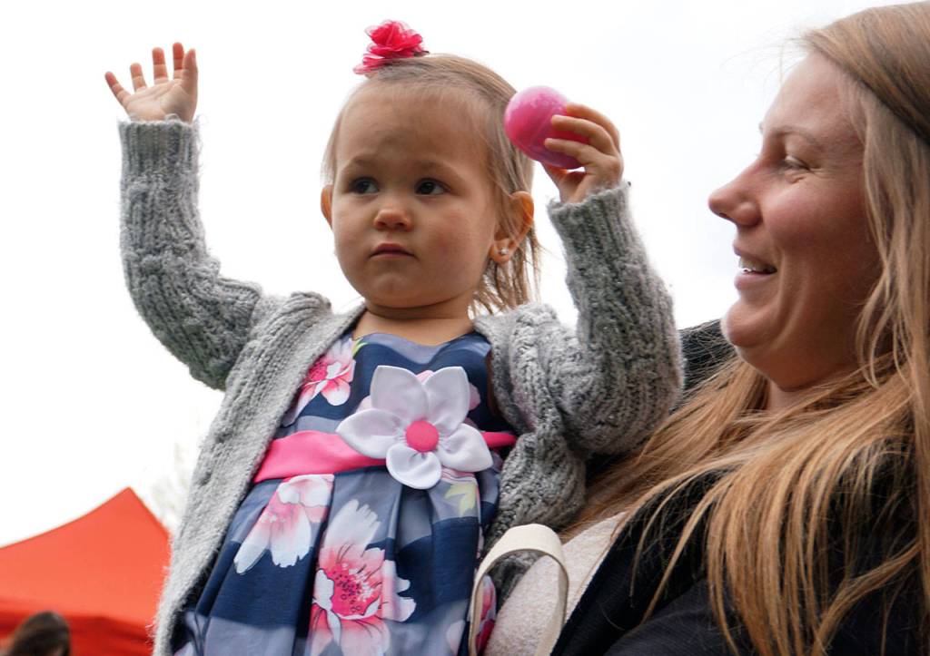 Rosemarie Hill, 1 1/2, waves around an Easter egg she nabbed April 20 at South Kitsap Regional Park. (Bob Smith | Kitsap Daily News)