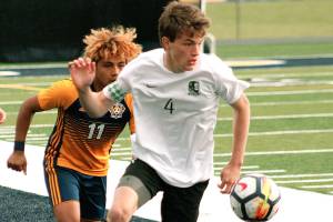 Klahowyas Aaron Becker flips the ball ahead of a Forks player in his teams 1A state tournament game. (Mark Krulish/Kitsap News Group)
