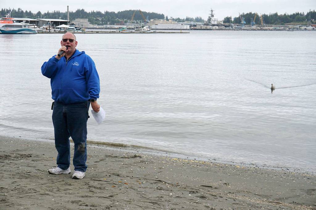 Matt Murphy begins to wrap up the Seagull Calling Contest Saturday just as a seagull straggler steams to shore looking for any remaining treats left by contestants. (Bob Smith | Kitsap Daily News)