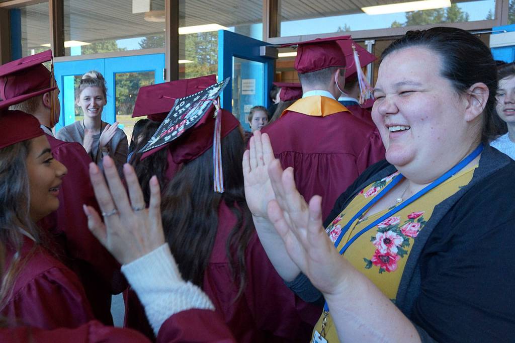Sedgwick Middle School teacher Janine Chalmers high-fives returning middle-school alums and now graduating South Kitsap high-schoolers. (Bob Smith | Kitsap Daily News)