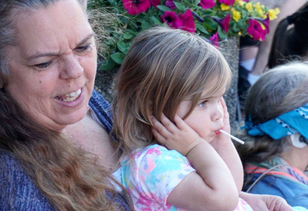 As the South Kitsap Fire and Rescues contingent of fire engines blast their horns during the parade, a youngster pinches her ears to block the noise. (Bob Smith | Kitsap Daily News)