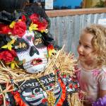 Alice Taylor, 4, of Port Orchard found her favorite scarecrow  a creation highlighted by a colorfully painted face mask, submitted by Home Made Cafe in the scarecrow contests Business category. (Bob Smith | Kitsap Daily News)
